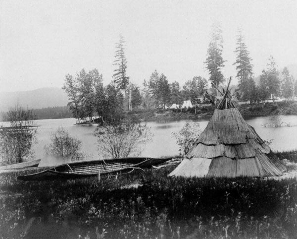 a teepee and canoe set alongside the river